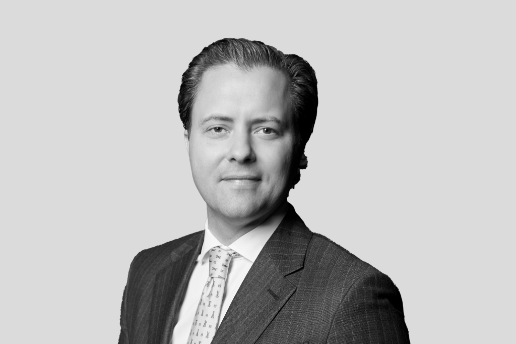 Porträt eines Mannes im Anzug vor grauem Hintergrund.